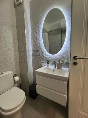 La salle de bains est pourvue de toilettes, d'un lavabo et d'un miroir. dans l'établissement Sunny breeze apartment, à Vlorë