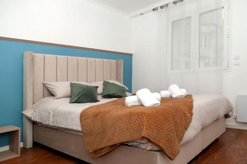 Un dormitorio con una cama grande con almohadas verdes y blancas. en Élégant appartement aux portes de paris, en Saint-Ouen