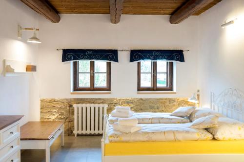 a bedroom with a bed and a table and windows at Statek Poštolka in Svitavy