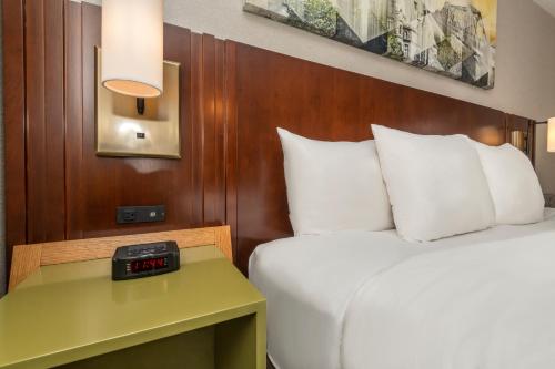 a hotel room with a bed and a clock on a table at Comfort Inn East in Sudbury