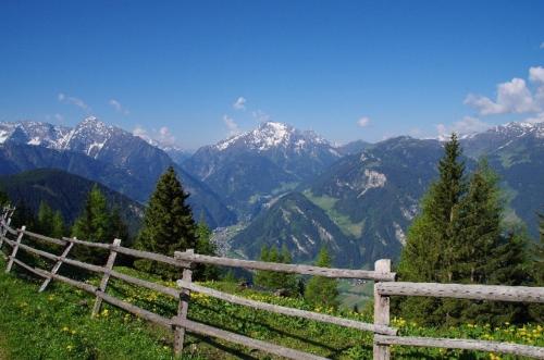 a wooden fence on a hill with mountains in the background at Hotel Sportalm in Gerlos