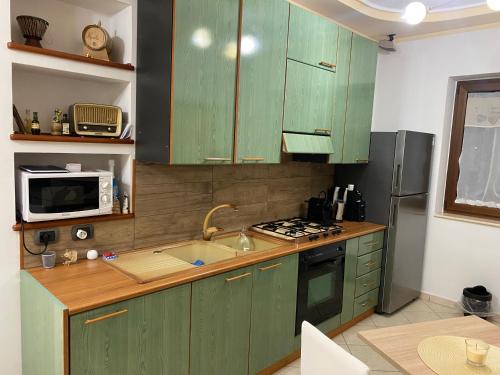 cocina con armarios verdes, fregadero y microondas en Aqua Pompeiana, en Scafati