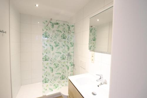 a bathroom with a sink and a shower curtain at Recreatiedomein Warredal - The Lodge in Neeroeteren