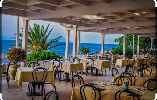 un restaurant avec des tables et des chaises et l'océan dans l'établissement Casa Vacanza da LUCIA&PINA, à Piraino