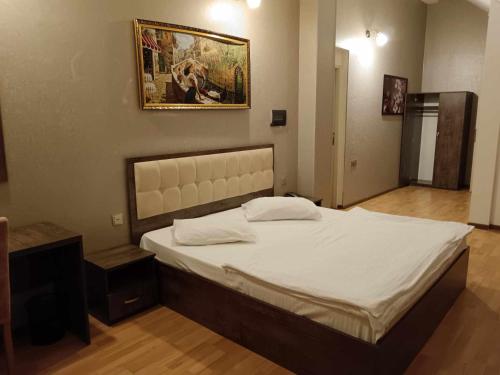 a large bed in a bedroom with a picture on the wall at soprano guest house in Baku