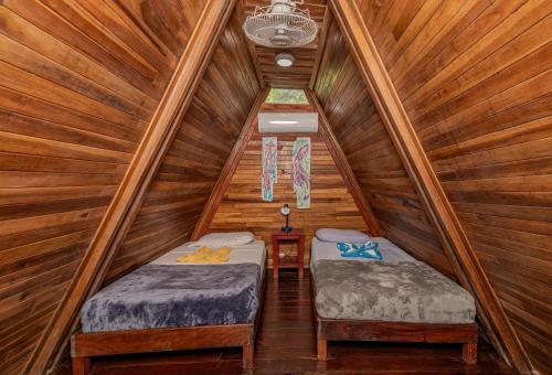 a bedroom with two beds in a wooden cabin at Playa Grande Surf Camp in Playa Grande