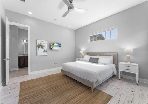biała sypialnia z łóżkiem i wentylatorem sufitowym w obiekcie Luxurious Ocean View 3BD House In Jacksonville w mieście Jacksonville Beach