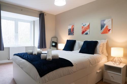 a bedroom with a large white bed with blue pillows at Entire 4 Bed Cosy Luxury Spacious house in Huntingdon