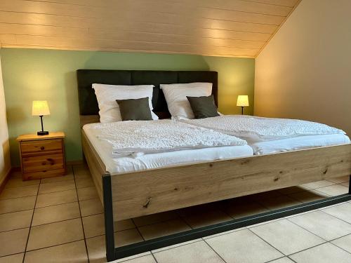a bedroom with a large wooden bed with two lamps at Ferienapartments Eifel Stay in Lissendorf
