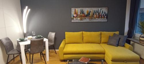a living room with a yellow couch and a table at Gemütliches helles Apartment mit Balkon und Parkplatz vor der Tür im Zentrum von Bayreuth in Bayreuth