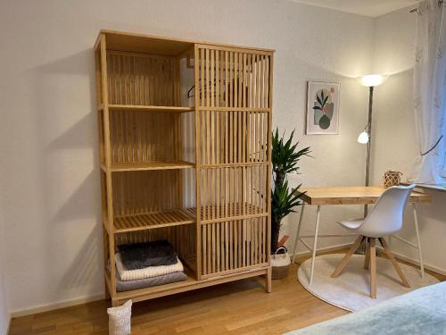 a wooden book shelf in a room with a desk at Gemütliches helles Apartment im Zentrum von Bayreuth in Bayreuth