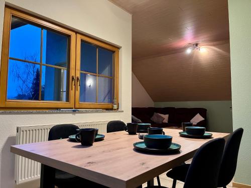 a large wooden table with chairs and a large window at Ferienapartments Eifel Stay in Lissendorf