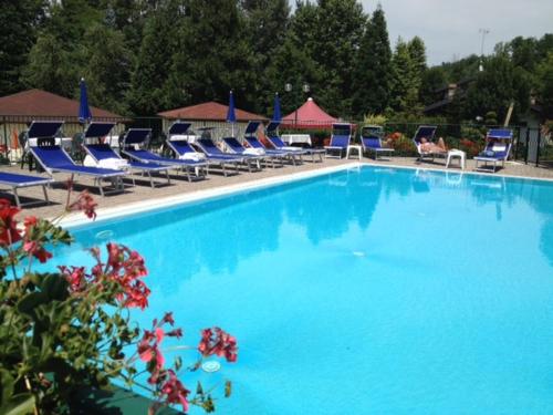 a large blue swimming pool with blue lounge chairs at Hotel La Ruota in Pianfei
