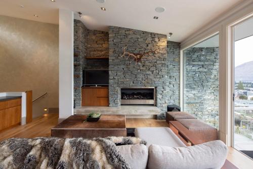 a living room with a stone fireplace at Villa Antrim- Lake Views- Gas Fire- Hot Tub in Queenstown