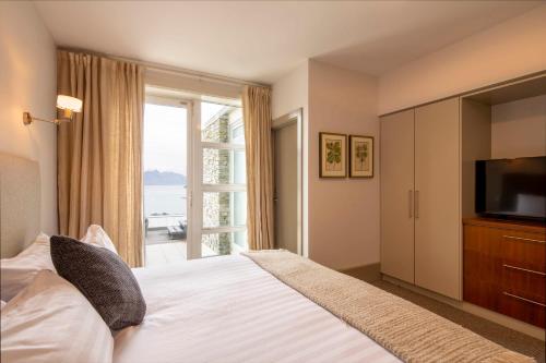 a bedroom with a bed with a television and a window at Villa Antrim- Lake Views- Gas Fire- Hot Tub in Queenstown