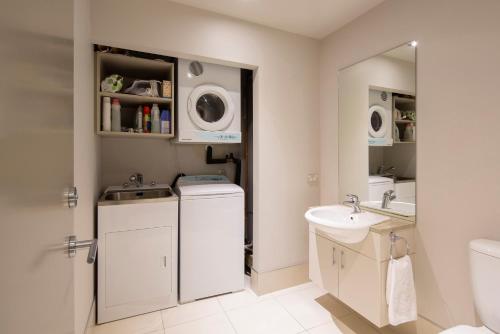 a white bathroom with a sink and a washing machine at Villa Antrim- Lake Views- Gas Fire- Hot Tub in Queenstown
