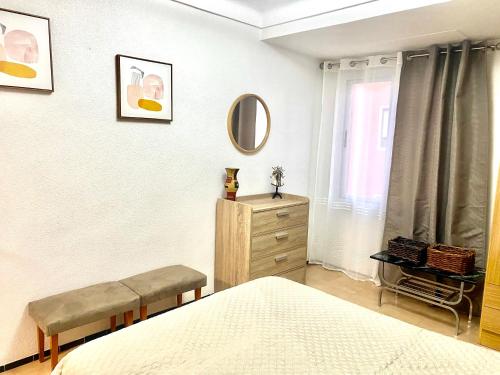 a bedroom with a bed and a dresser and a mirror at Затишна квартира Playa Levante in Santa Pola