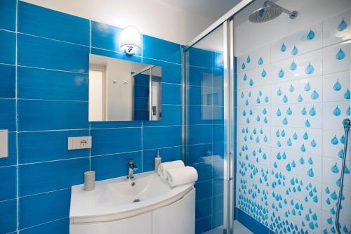 YourHome - H2O Marina Apt Sea View في بوسيتانو: حمام أزرق مع حوض ومرآة