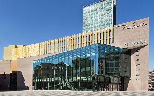 a large glass building with a tall building at Station 64 B2 Charleroi-Airport in Charleroi