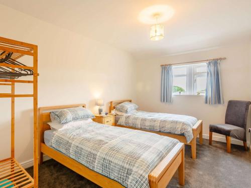 a bedroom with two beds and a chair at 3 Bed in Denby Dale 88924 in Denby Dale