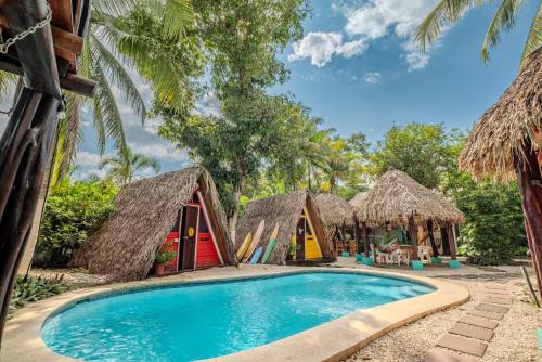 a group of huts and a swimming pool in a resort at Playa Grande Surf Camp in Playa Grande