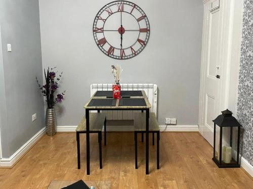 uma sala de jantar com uma mesa e um grande relógio na parede em Orlando Llandundo Apartment em Llandudno