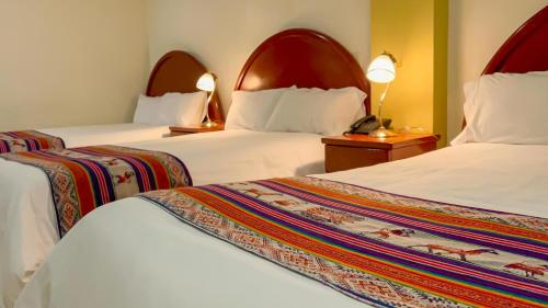 um quarto de hotel com duas camas e duas lâmpadas em La Mansion Casa Hotel em Andahuaylas