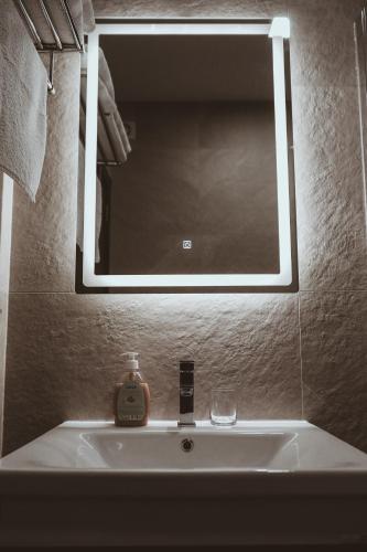 a bathroom sink with a mirror and a soap dispenser on it at S Apart Rooms in Bosanska Gradiška