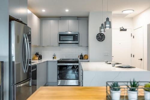 una cocina con armarios blancos y electrodomésticos de acero inoxidable en Revelstoke Alpine Retreat - RARE One-Bedroom Condo, en Revelstoke