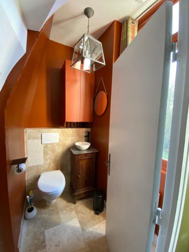 La salle de bains est pourvue de toilettes et d'un escalier aux murs orange. dans l'établissement le Pavillon d'Hermières, proche Disneyland Paris, à Favières