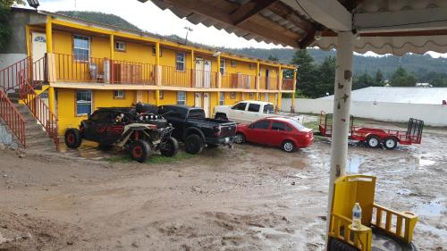 grupa samochodów osobowych i ciężarowych zaparkowanych przed budynkiem w obiekcie Hotel y Cabañas Cascada de Basaseachi 