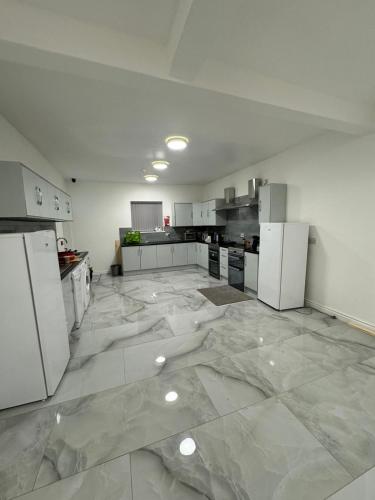 eine große Küche mit weißen Geräten auf einem Marmorboden in der Unterkunft VicVic Guest house in Oldham