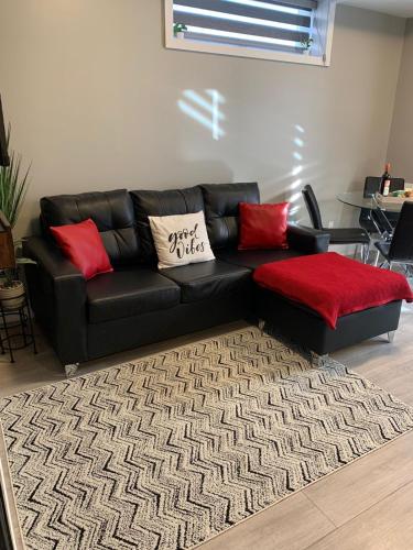 a black leather couch in a living room with red pillows at Niagara Getaway across Fallsview in Niagara Falls