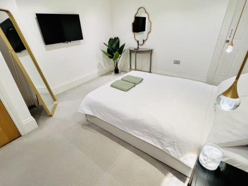 a white bedroom with a bed and a tv at Soho Apartments in London