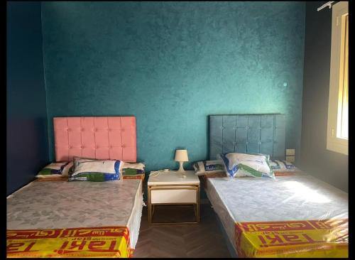 2 Einzelbetten in einem Zimmer mit grünen Wänden in der Unterkunft shebin in Shibīn al Kawm
