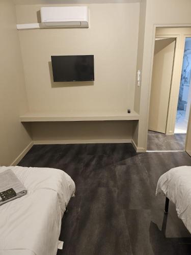 une chambre avec deux lits et une télévision au mur dans l'établissement MAISON ACTI SUD Tout confort - Zone commerciale CHENOVE, à Chenôve