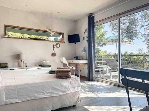 une chambre avec un lit et un bureau et un balcon dans l'établissement Vue Mer Cabane chic dans l'Olivier, Piscine, à Nice