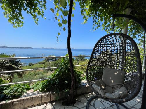 a wicker chair sitting on a porch with a view of the ocean at Holiday Apartment Lira jacuzzi - sea view- terrace in Mlini