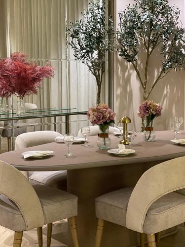 a dining room table with chairs and flowers on it at شقة فاخرة بمدخل طراز سلماني in Riyadh
