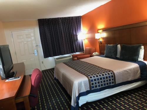 a hotel room with a bed and a desk and a television at Howard Johnson by Wyndham Perry GA in Perry
