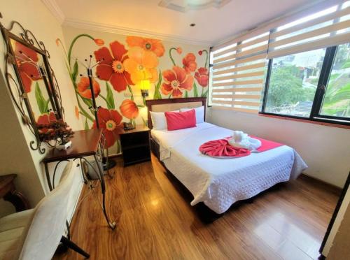 1 dormitorio con 1 cama con flores en la pared en Hotel Virgen del Cisne en Loja