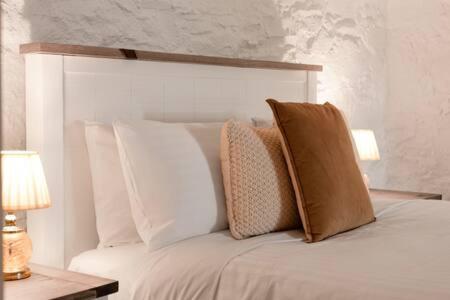 un letto bianco con cuscini sopra di Funky Heritage Home in the City Center a Launceston