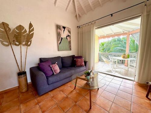 uma sala de estar com um sofá azul e uma mesa em Passiflora em Orient Bay