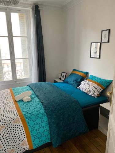 - un lit avec une couette bleue dans une chambre dans l'établissement Joli petit 2 pièces, à Asnières-sur-Seine