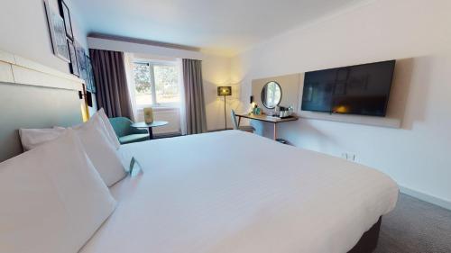 a hotel room with a large white bed and a tv at Holiday Inn Cambridge by IHG in Cambridge