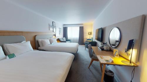 a hotel room with two beds and a desk at Holiday Inn Cambridge by IHG in Cambridge
