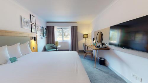 a hotel room with a large bed and a desk at Holiday Inn Cambridge by IHG in Cambridge