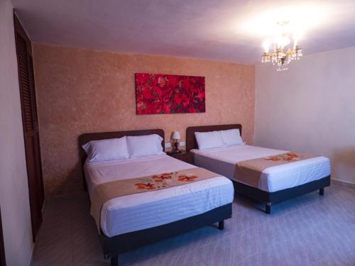 a hotel room with two beds and a painting on the wall at Hotel Boutique Flores y Gemas in Mérida
