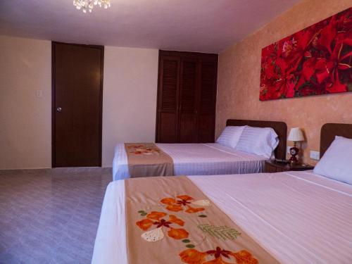 a hotel room with two beds and a painting on the wall at Hotel Boutique Flores y Gemas in Mérida