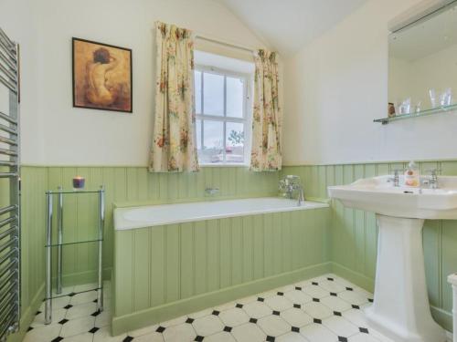 a green bathroom with a tub and a sink at 2 Bed in Caldbeck SZ212 in Caldbeck